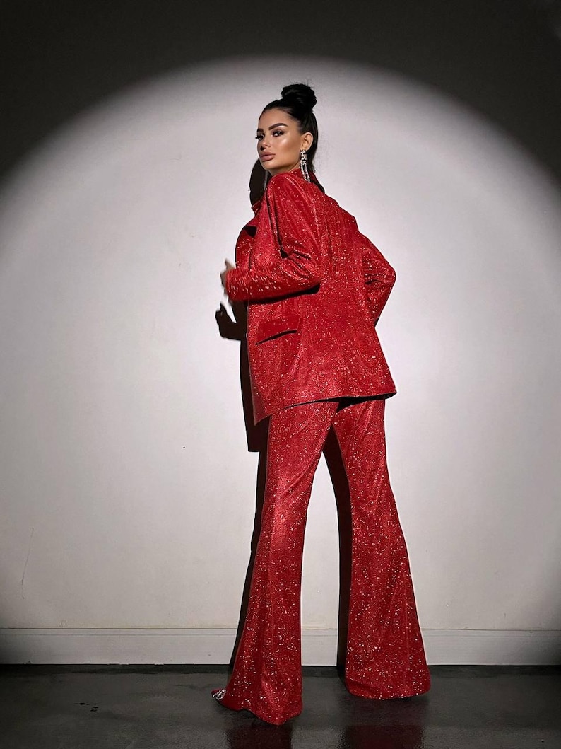 May include: A red sparkly pantsuit with a blazer and flared pants. The pantsuit is made of a soft, comfortable fabric and has a flattering fit.