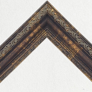 Könnte beinhalten: Ein dekorativer Bilderrahmen mit einer dunkelbraunen Holzoptik und goldenen Akzenten. Der Rahmen hat ein detailliertes, verziertes Design mit einem erhöhten Rand.