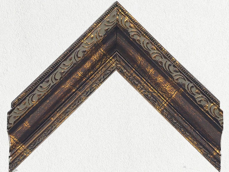 Puede incluir: Un marco de imagen decorativo con un acabado de madera marr&oacute;n oscuro y detalles dorados. El marco tiene un dise&ntilde;o ornamentado detallado con un borde elevado.