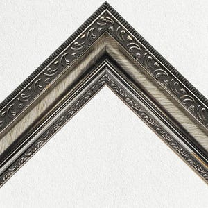 Peut inclure: Un cadre photo argenté avec un design décoratif et orné. Le cadre a une bordure surélevée et texturée avec une finition argentée.