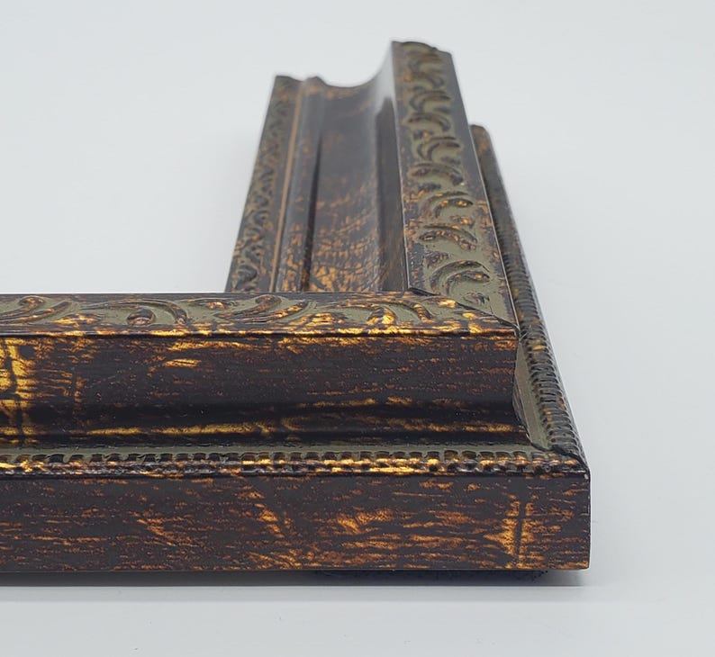 Puede incluir: Un marco de imagen marr&oacute;n oscuro con un dise&ntilde;o adornado dorado y verde. El marco tiene un acabado desgastado.