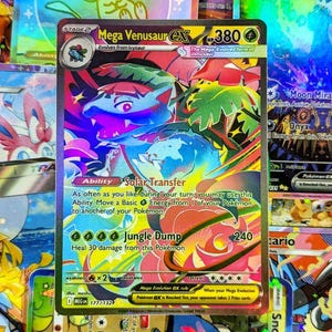 Può includere: Una carta collezionabile Pokémon Mega Venusaur EX olografica. La carta presenta un'illustrazione colorata del personaggio con il testo "Solar Transfer" e "Jungle Dump". La carta è circondata da altre carte Pokémon.