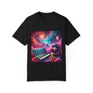 Op de afbeelding: Zwart T-shirt met een kleurrijke galaxy print met een astronaut die een synthesizer bespeelt. De helm van de astronaut heeft een gloeiend licht van binnen.
