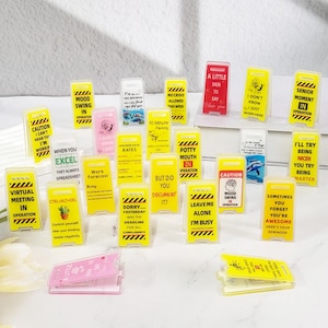 May include: A collection of 20 yellow and black caution signs with various humorous messages. The signs are made of clear plastic and have a black and yellow striped design. The signs are all different sizes and shapes, and they are all arranged in a random order.