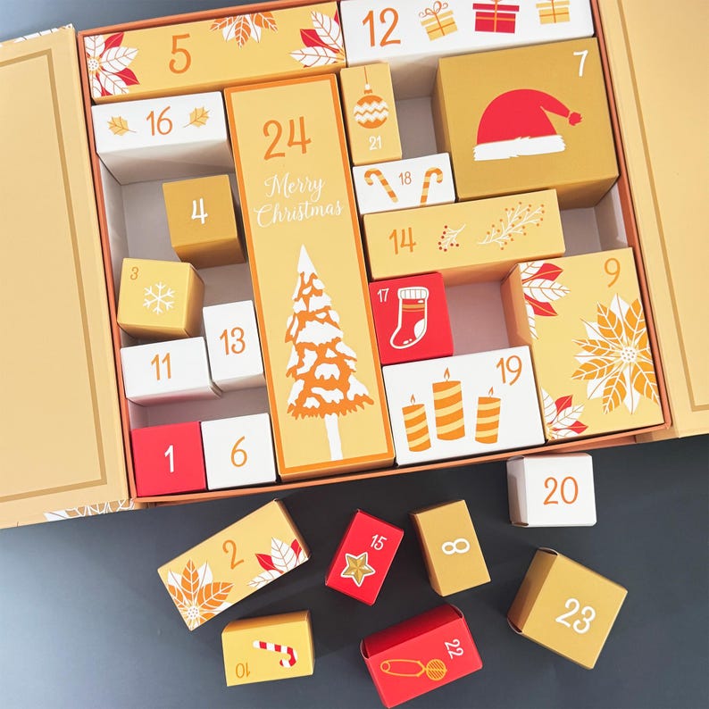May include: An open advent calendar with numbered boxes in shades of gold, white, and red. The boxes are decorated with Christmas-themed illustrations, including a Christmas tree, Santa hat, and ornaments. The text "Merry Christmas" is visible.