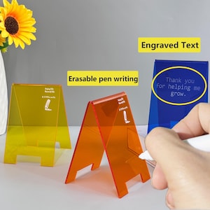 May include: Three colourful acrylic A-frame signs. One is yellow, one is orange, and one is blue. The blue sign has the text "Thank you for helping me grow." The signs are designed for erasable pen writing and engraved text.