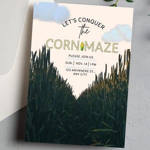 May include: An invitation card with the text "LET'S CONQUER the CORN MAZE" and event details. The card features a photograph of a corn maze and light blue cloud illustrations. An envelope is visible in the background.