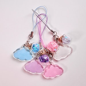 May include: Set of five colourful cloud-shaped phone charms with small glass globes filled with glitter. Each charm has a different colour cloud and glitter combination.