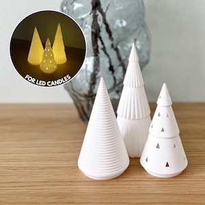 Może przedstawiać: Białe ceramiczne dekoracje choinkowe w różnych wzorach. Jedna choinka ma spiralny wzór, druga pionowe linie, a trzecia trójkątne wycięcia. Tekst "FOR LED CANDLES" znajduje się w okręgu.