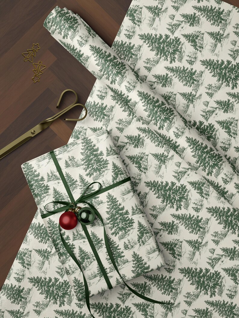 May include: Gift wrapping paper with a green and white forest pattern. A wrapped gift is adorned with a green ribbon and two ornaments. A roll of paper, scissors, and tree-shaped paper clips are also visible.