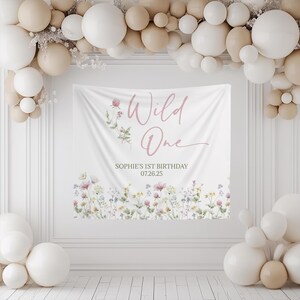 Floral 1st birthday welcome sign featuring a watercolor-style wildflower design at the bottom. The sign reads 'Wild One' with a small flower illustration, highlighting the celebration of a 1st birthday. Ideal as a photo backdrop or decoration for girls 1st birthday parties, creating a festive and elegant atmosphere.