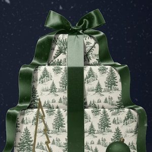 May include: A stack of wrapped gifts with a forest scene pattern, tied with a dark green satin ribbon and bow. A gold-colored metal Christmas tree and a green ornament are placed in front of the gifts.