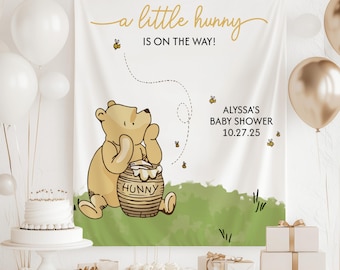 May include: A white backdrop with a Winnie the Pooh illustration, a honey pot, and bees. The text reads "a little hunny is on the way!" and "Alyssa's Baby Shower 10.27.25".