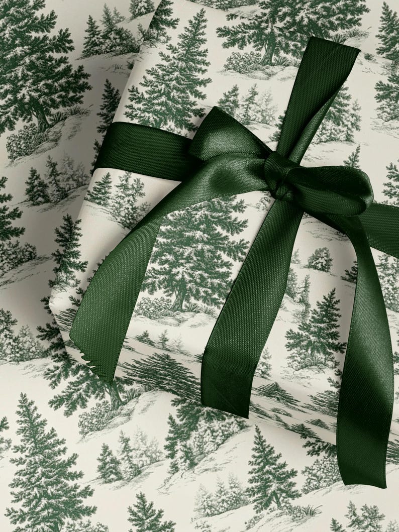 May include: A wrapped gift with a forest-themed pattern in green and white. The wrapping paper features a repeating design of pine trees and hills. A dark green satin ribbon is tied in a bow around the package.