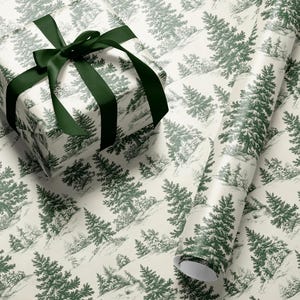 May include: A wrapped gift box and a roll of wrapping paper featuring a green and white forest scene. The gift box is tied with a dark green satin ribbon. The wrapping paper has a repeating pattern of evergreen trees.