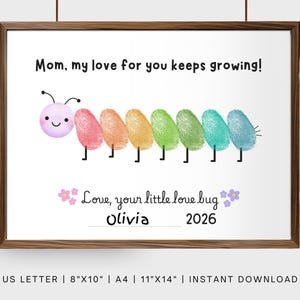 Op de afbeelding: Een ingelijste print met een bruine houten lijst. De print toont een kleurrijke rups gemaakt van vingerafdrukken, met de tekst "Mom, my love for you keeps growing!" en "Love, your little love bug Olivia 2026".