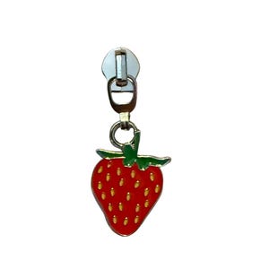 May include: A silver-toned metal zipper pull featuring a dangling strawberry charm. The strawberry is enameled in bright red with a green stem and small yellow seed details. The charm is attached to a standard metal zipper slider mechanism.
