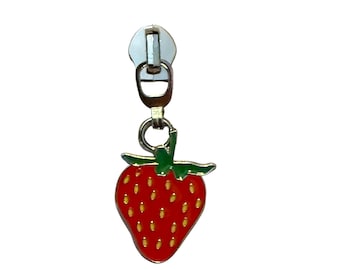May include: A silver-toned metal zipper pull featuring a dangling strawberry charm. The strawberry is enameled in bright red with a green stem and small yellow seed details. The charm is attached to a standard metal zipper slider mechanism.