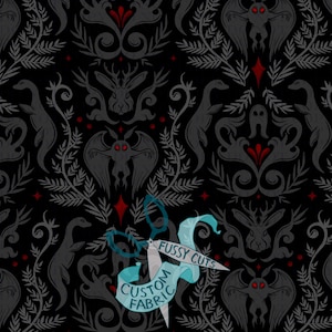 May include: Black fabric with a repeating pattern of gray gothic-style illustrations, including a moth, a rabbit, and a dinosaur-like creature. Red diamond shapes and floral elements accent the design. The text "FUSSY CUTS CUSTOM FABRIC" is on a blue ribbon.