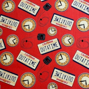 Könnte beinhalten: Roter Stoff mit einem sich wiederholenden Muster aus Uhren, Nummernschildern mit der Aufschrift "California Outatime" und einem kleinen schwarzen Gerät mit einem roten Kabel. Die Nummernschilder sind gelb mit schwarzer Beschriftung.