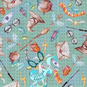 Peut inclure: Motif aquarelle avec des éléments de sorcellerie : chapeau, lunettes, baguettes et clés volantes. Le motif comprend le texte "Fussy Cuts Custom Fabric" sur une bannière, sur fond vert clair.