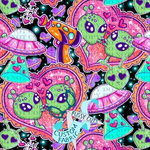 May include: A vibrant, repeating pattern featuring green aliens with large eyes, hearts, and spaceships. The design includes a ray gun, hearts, and the text "Fussy Cuts Custom Fabric" on a black background with sparkling accents.