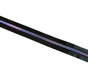 Puede incluir: Una cremallera negra con una espiral de colores del arcoíris. La cinta de la cremallera es negra y la espiral hace la transición del morado al azul. La cremallera está en diagonal sobre un fondo blanco.