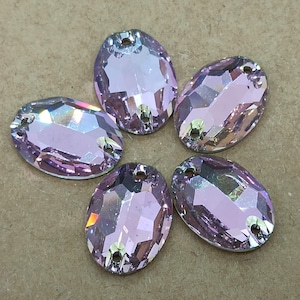 May include: Five oval-shaped, iridescent, light purple rhinestones with two holes each.