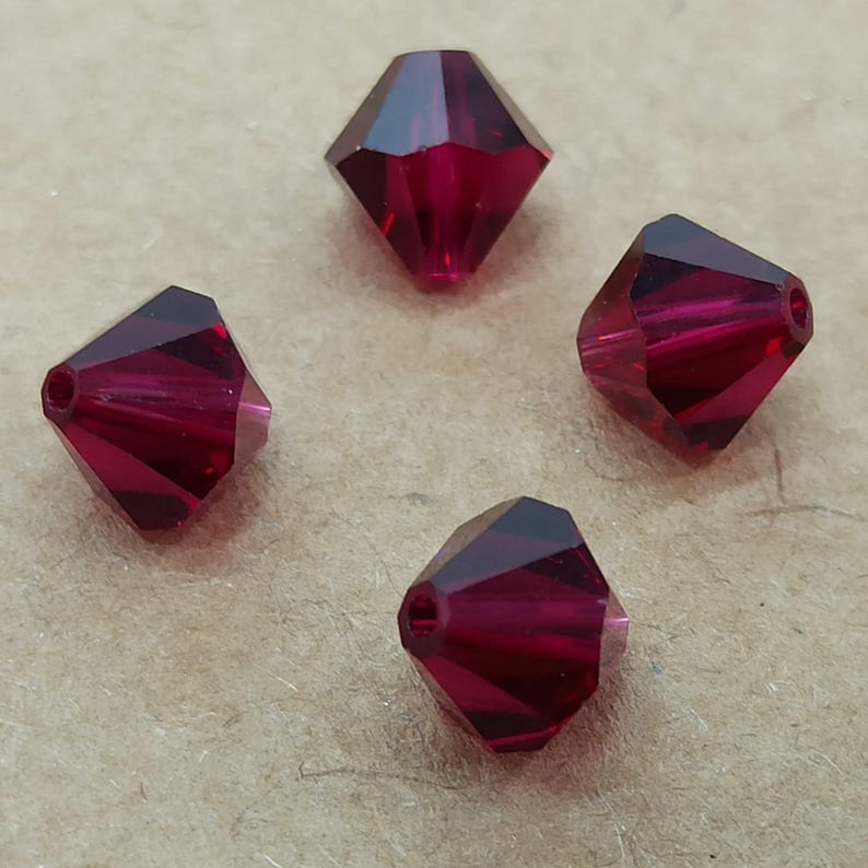 May include: Four deep red crystal beads with a faceted diamond shape.