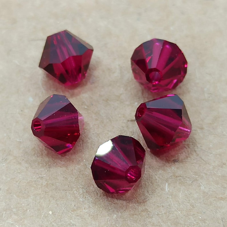 May include: Five faceted, ruby red, glass beads with a hole in the center for stringing.