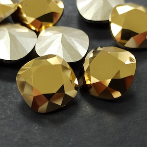 May include: Close-up of several faceted, gold-colored, and silver-colored decorative gems. The gems have a geometric design with multiple facets, reflecting light. The gold gems are a warm, shiny color, while the silver gems are a cooler, matte color.