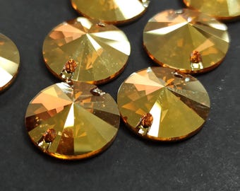 May include: Close-up of several faceted, round, amber-colored crystal beads. Each bead has a central hole and a multi-faceted surface that reflects light. The beads are arranged on a dark surface.