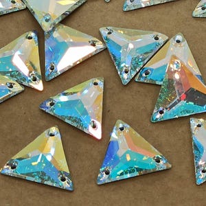 Puede incluir: Una colección de piedras de cristal triangulares iridiscentes con un diseño claro y facetado. Las piedras de cristal tienen un brillo arcoíris y son perfectas para agregar brillo a las manualidades y las joyas.