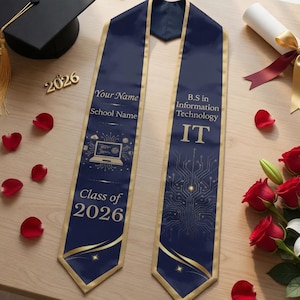 May include: A graduation sash with gold trim and the text "B.S in Information Technology IT" and "Class of 2026". A black graduation cap, diploma, and bouquet of red roses and white lilies are also present.