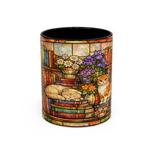 Puede incluir: Taza de cer&aacute;mica con un dise&ntilde;o de vidriera que representa una escena de biblioteca con gatos. El dise&ntilde;o incluye un gato durmiendo, un gato sentado, estanter&iacute;as y flores. La taza tiene un interior negro.