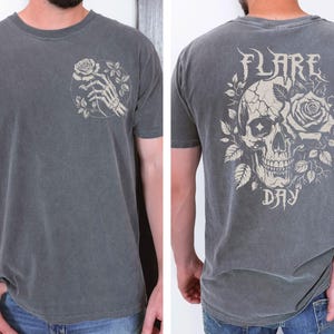 May include: A gray t-shirt with a skull and rose graphic on the back and a skeleton hand holding a rose on the front. The text "FLARE DAY" is printed below the skull and rose graphic.