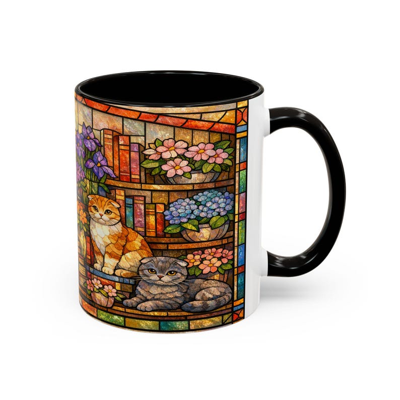 Puede incluir: Taza de cer&aacute;mica blanca con interior y asa negros. La taza presenta un colorido dise&ntilde;o de vidriera con dos gatos, libros y flores. El dise&ntilde;o incluye tonos naranja, gris, rosa, azul y morado.