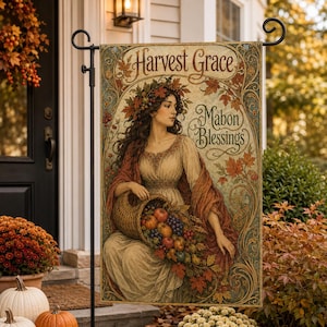 May include: A rectangular garden flag featuring an illustration of a person with long hair wearing a wreath of autumn leaves, holding a cornucopia filled with fruit. The text Harvest Grace and Mabon Blessings is printed in a decorative font.