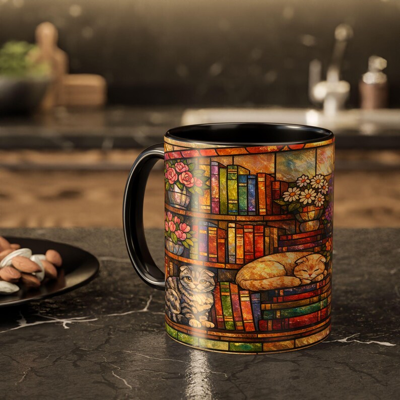 Puede incluir: Taza de cer&aacute;mica negra con un dise&ntilde;o de vidriera de colores que representa una estanter&iacute;a, flores y dos gatos. La taza tiene un asa y un interior negros, ideal para caf&eacute; o t&eacute;.