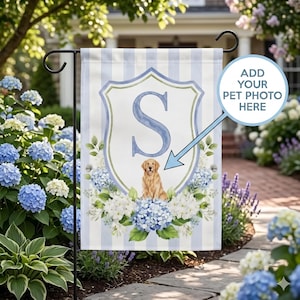 May include: A garden flag with light blue and white vertical stripes featuring a central crest with the letter S, a golden retriever illustration, and blue and white hydrangea flowers. A circular text bubble says ADD YOUR PET PHOTO HERE.