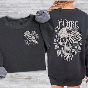 May include: Black sweatshirt with a skull and rose graphic on the back and a skeleton hand holding a rose on the front. The text "FLARE DAY" is printed below the skull.
