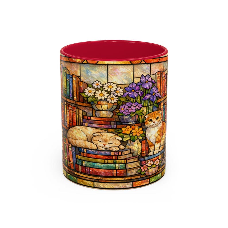 Puede incluir: Taza de cer&aacute;mica con un dise&ntilde;o de vidriera que representa una escena de biblioteca con libros, flores y dos gatos. El interior de la taza es rojo. El dise&ntilde;o envuelve la taza, mostrando un tema art&iacute;stico y acogedor.
