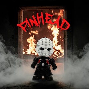 May include: A Pinhead figure stands before a fiery backdrop. The figure has a white head with numerous pins, black eyes, and a black outfit with red accents. The word "PINHEAD" is written in red above the figure.