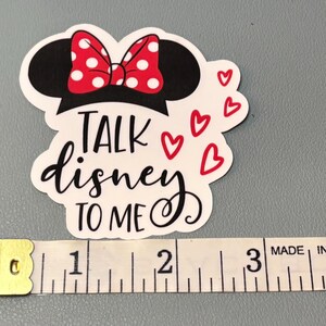 May include: White sticker with a black silhouette of Mickey Mouse's head with a red and white polka dot bow. The text "Talk Disney to me" is written in black cursive with red hearts around the text.