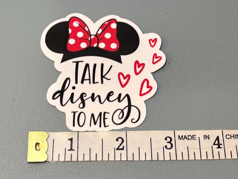 May include: White sticker with a black silhouette of Mickey Mouse's head with a red and white polka dot bow. The text "Talk Disney to me" is written in black cursive with red hearts around the text.