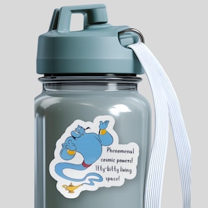 May include: A light blue water bottle with a carrying strap and a sticker featuring a blue genie and the text: Phenomenal cosmic powers! Itty-bitty living space! The genie is depicted with gold wrist cuffs and is positioned above a gold oil lamp.