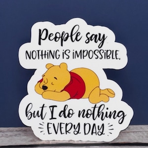 May include: White sticker with a cartoon Winnie the Pooh bear sleeping. The sticker says "People say nothing is impossible, but I do nothing every day."