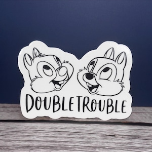 May include: A white sticker with a black outline of two chipmunk faces and the text "DOUBLE TROUBLE".