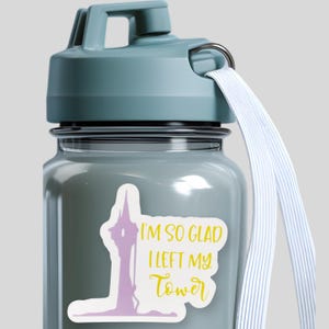 May include: A light blue water bottle with a screw-top lid and a white carrying strap. A sticker on the front features a purple silhouette of a tall tower and the yellow text "I'M SO GLAD I LEFT MY TOWER" in a mix of block and script fonts.