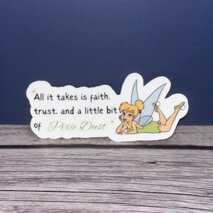 May include: A sticker featuring Tinkerbell, a fairy with green wings and a yellow dress, lying on her side. The sticker has the text "All it takes is faith. trust. and a little bit of Pixie Dust."